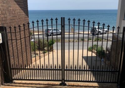 Double Gate by seaside in St Peters Design with Flat bar Arched top rails and extra row of Cardinal Spears at the bottom to keep little dogs in safe.